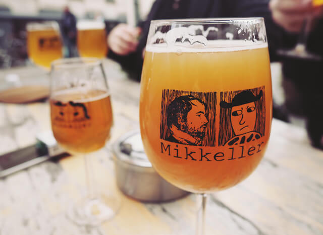 Table with mutliple full Mikkeller beer glasses