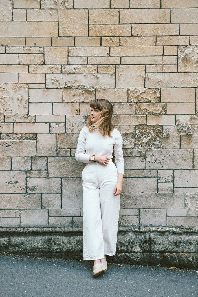 Lyzi wears an ivory outfit with lapis lazuli necklace, by Elinor John