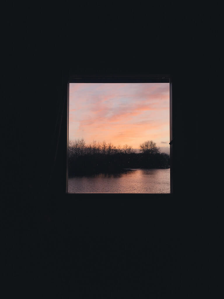 Sunset in the window at Log House Holidays lakeside cabin retreat in the Cotswolds