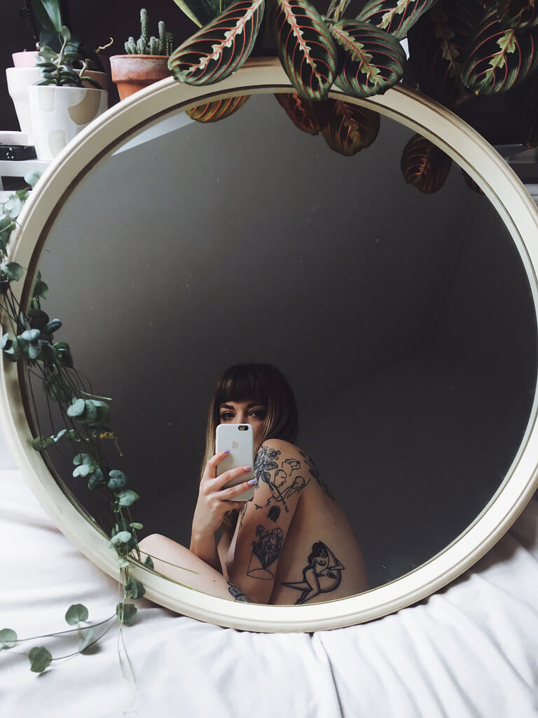 Lyzi Unwin shows off her tattoos in a round mirror