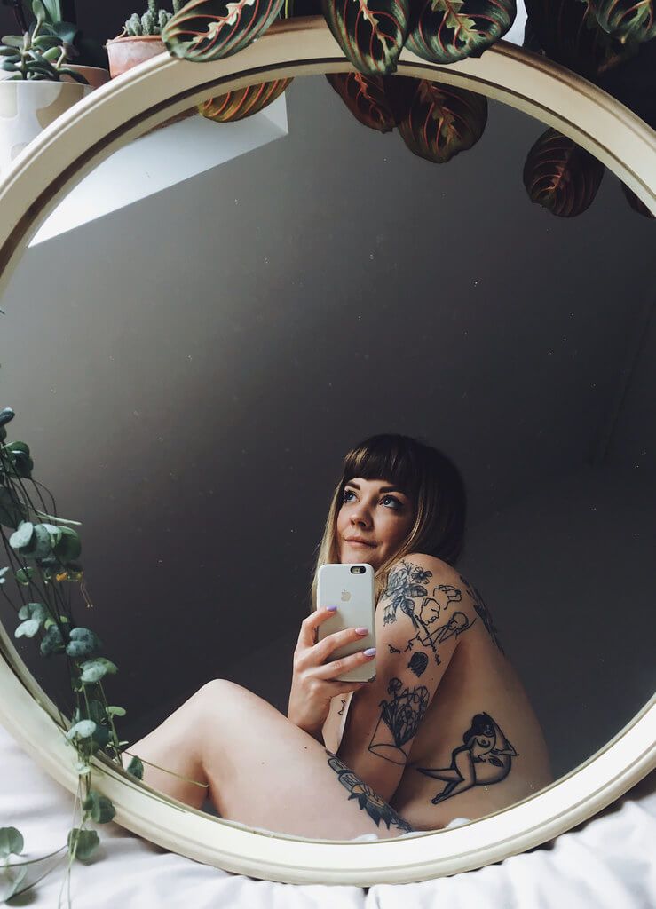 Lyzi Unwin shows off her tattoos in a round mirror