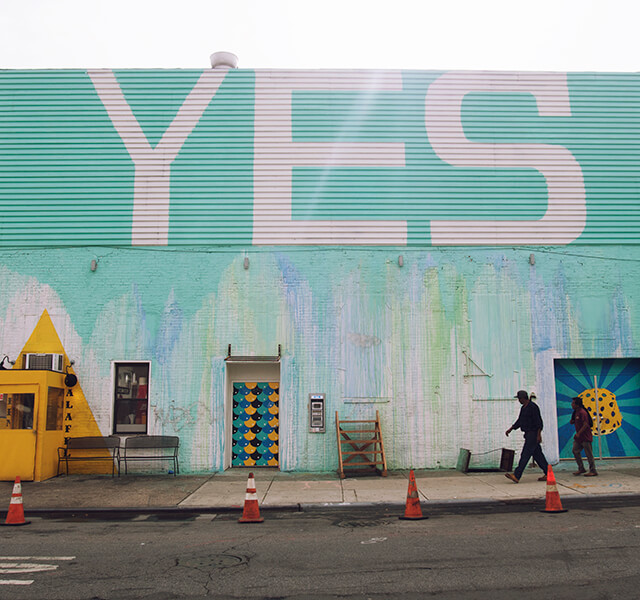 Turquoise wall with "YES" graffiti