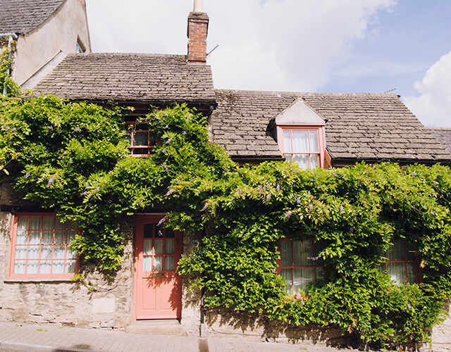 Pretty homes in Malmesbury, Cotswolds with pink door and windows and plants growing on the outside