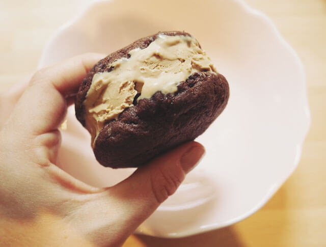 Hand holding a chocolate chip cookie & coffee ice cream sandwich