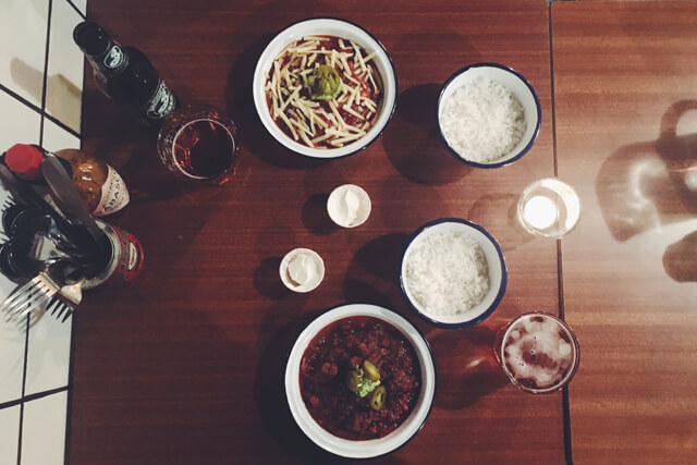 Table from above with bowls of chilli, rice and sour cream, with drinks