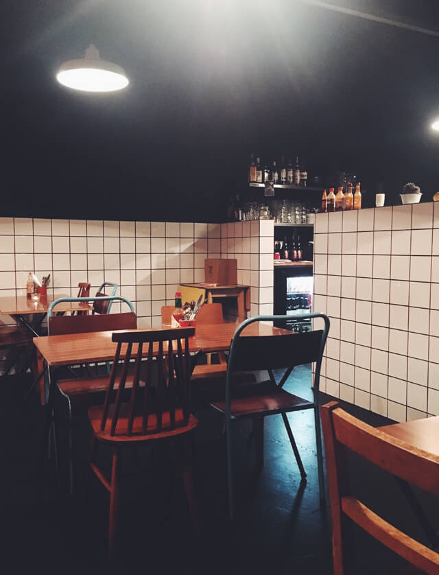 Interior of Mathilda's Chilli Bar, with black walls and white times, and vintage tables and chairs