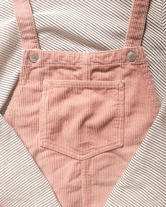 Flat lay of pink corduroy pinafore with diagonal striped top