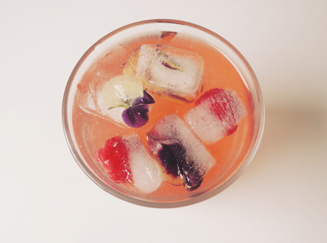 Glass of Gin & Tonic Blush cocktail from above, with floral ice cubes