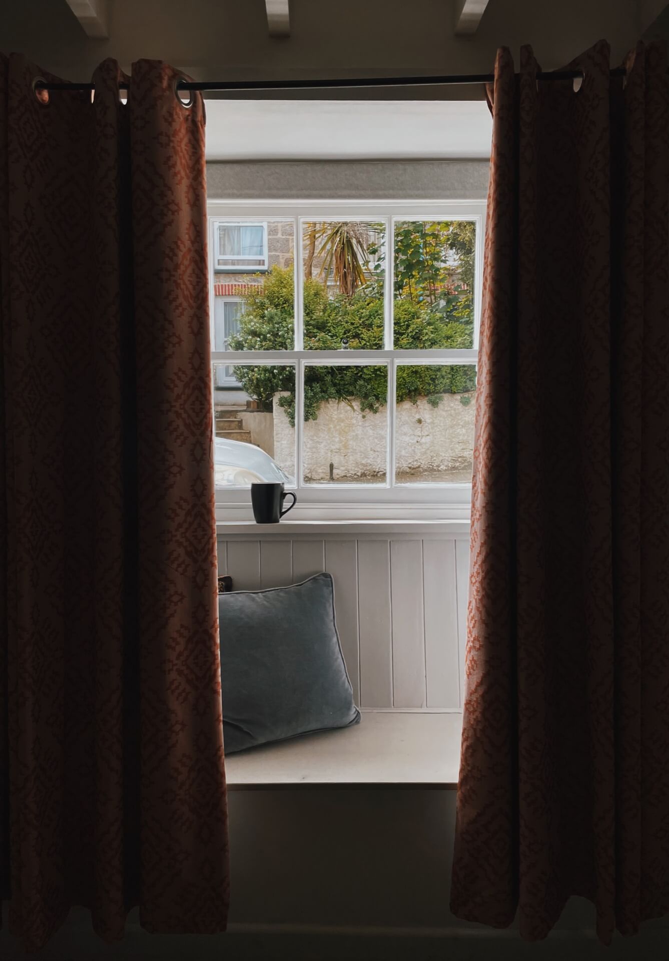 Cosy window seat with curtains and cup of tea