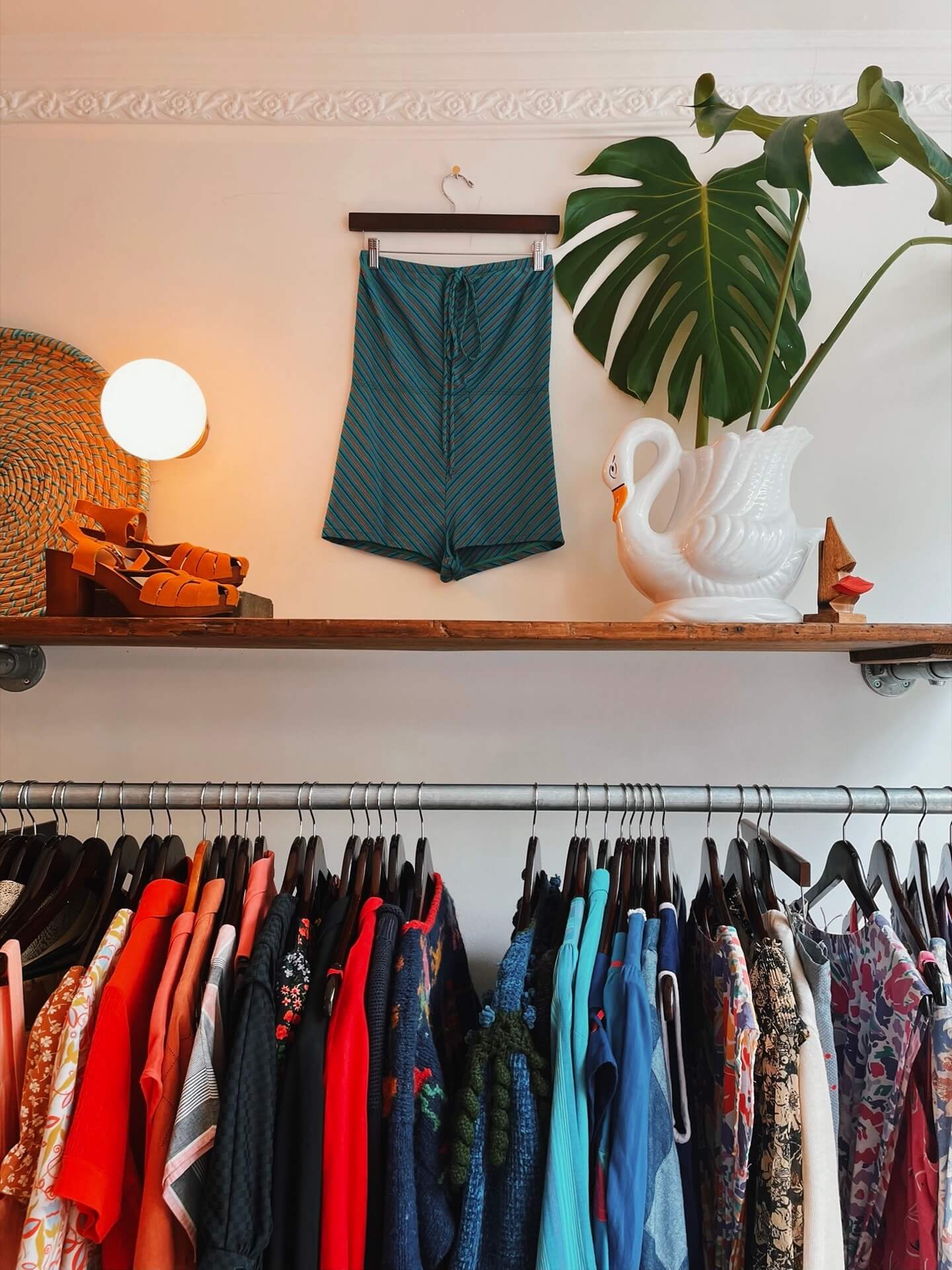 Display of clothes and swan vase inside Three of Cups Vintage shop in Penryn