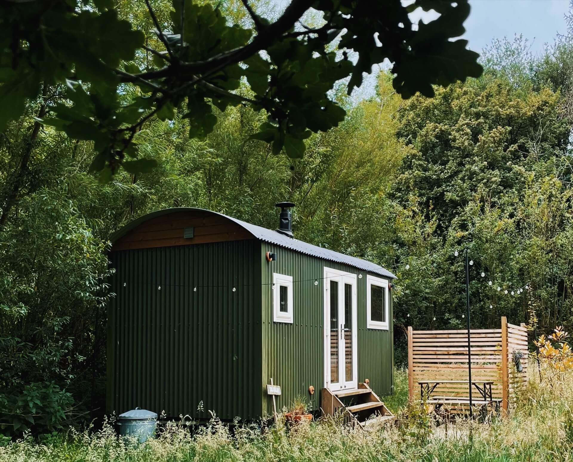 A green shepherds hut nestled among the trees