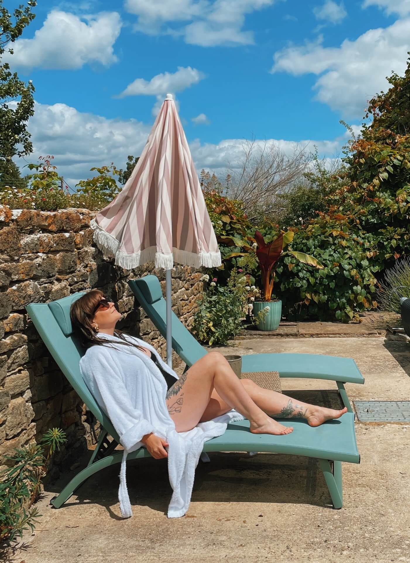 Lyzi on a sun lounger wearing a swimsuit and white robe