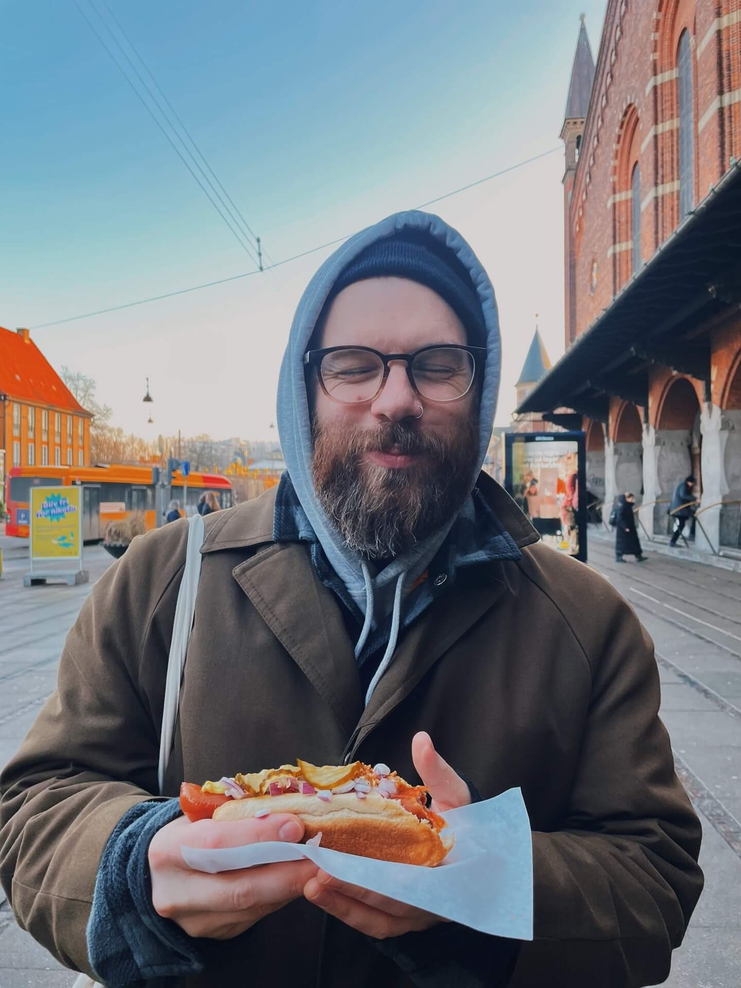 A blissed-out man holding a hot dog from John's Hotdog Deli Copenhagen